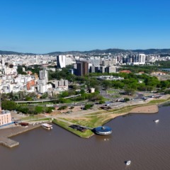 Vista aérea de Porto Alegre mostrando bairros residenciais e o Lago Guaíba ao fundo.