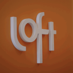 Logo da Loft em parede laranja do escritório da empresa, símbolo da marca de tecnologia e serviços financeiros do setor imobiliário