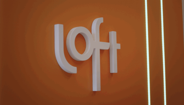 Logo da Loft em parede laranja do escritório da empresa, símbolo da marca de tecnologia e serviços financeiros do setor imobiliário