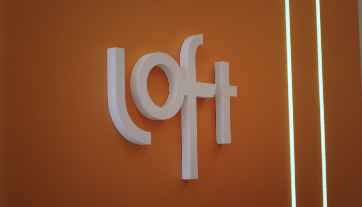 Logo da Loft em parede laranja do escritório da empresa, símbolo da marca de tecnologia e serviços financeiros do setor imobiliário